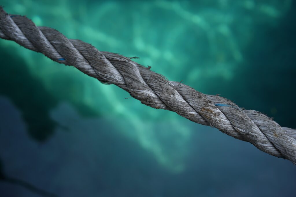 A rope pulled taught over a blue-green pool of water.